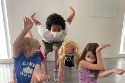 Four kids pose theatrically at a summer camp.