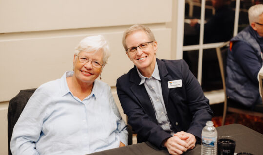 two people sitting at a table smiling for a picture