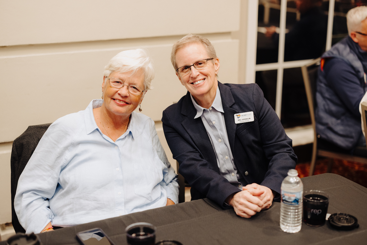 two people sitting at a table smiling for a picture