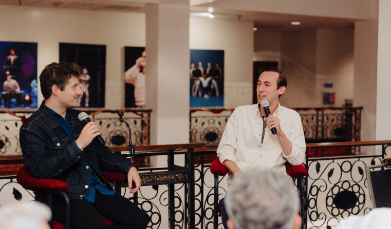 two men sitting next to each other and speaking into microphones