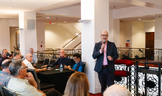 man standing in front of a group talking into a microphone