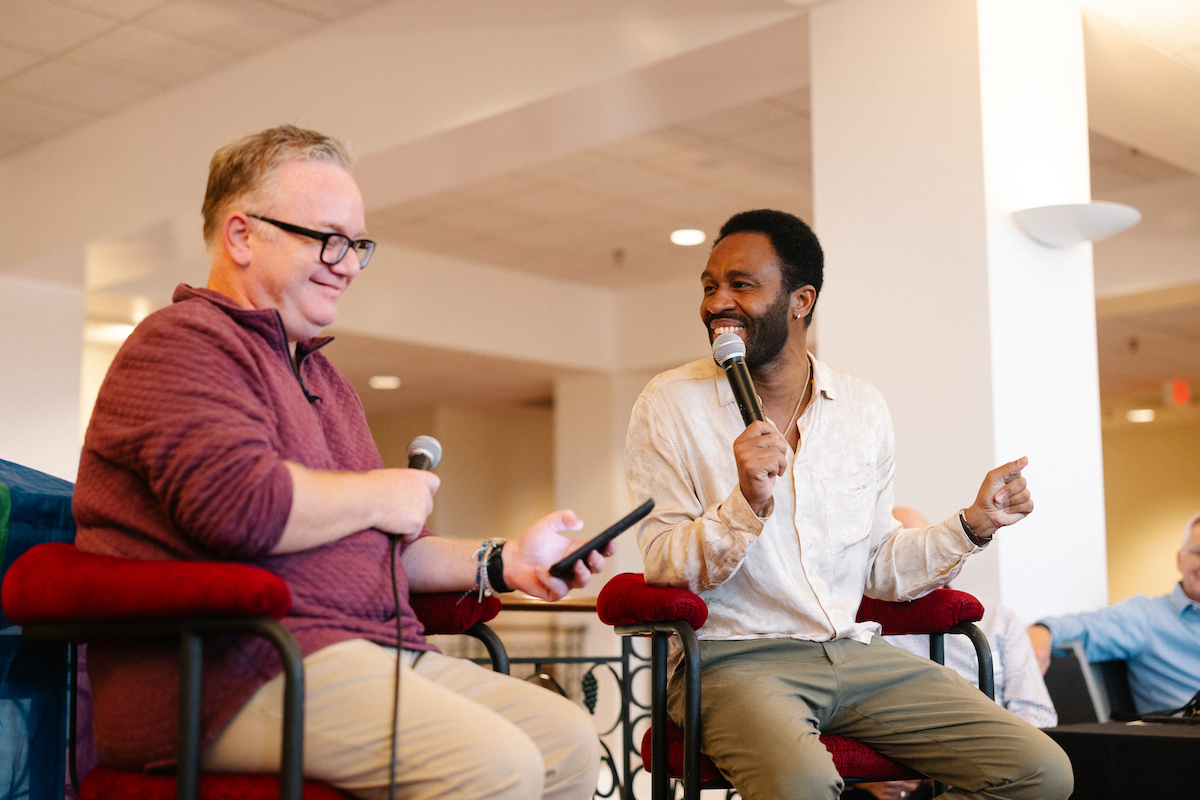 two men sitting in chairs speaking into microphones