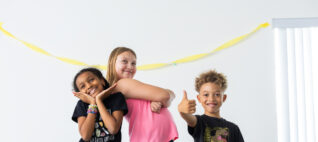 Three children pose theatrically for a photo.