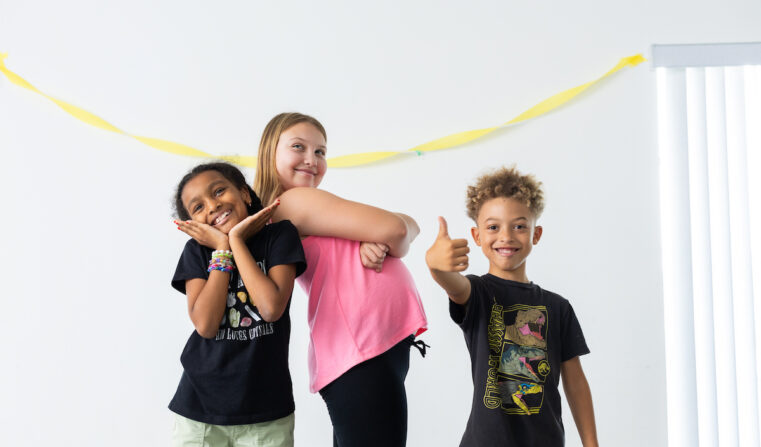 Three children pose theatrically for a photo.
