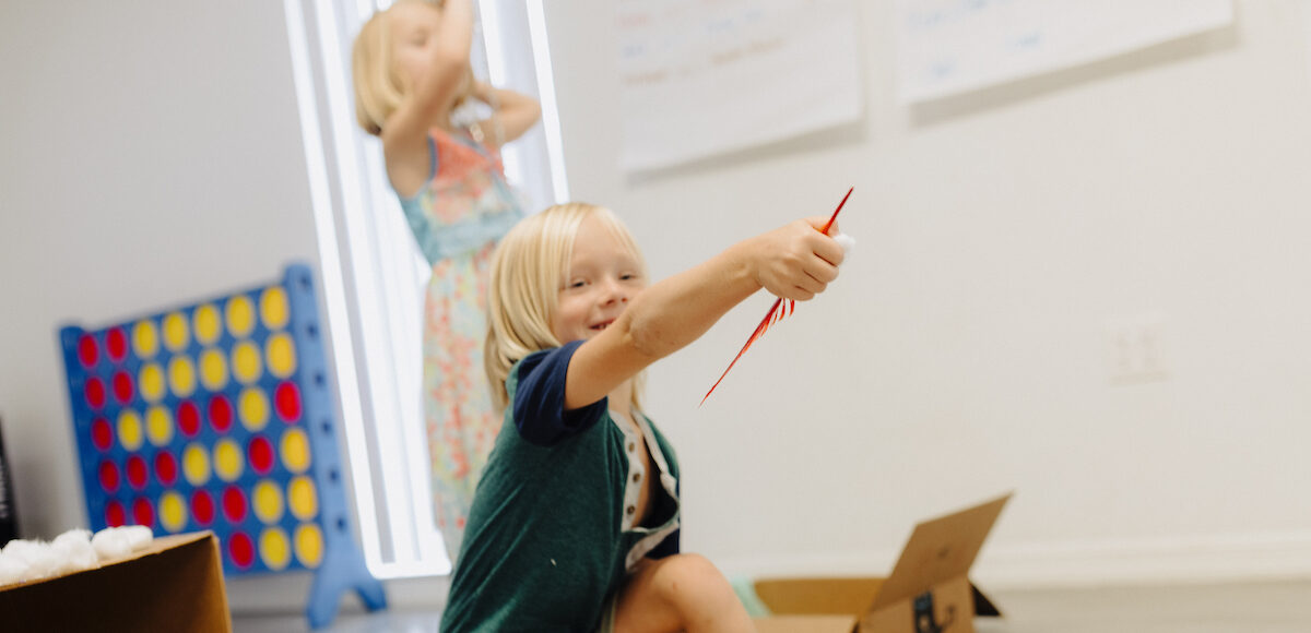 A young boy plays with craft supplies at camp.