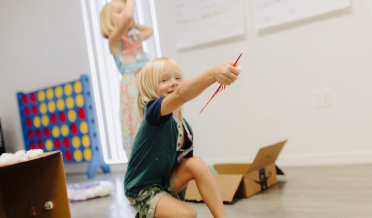 A young boy plays with craft supplies at camp.