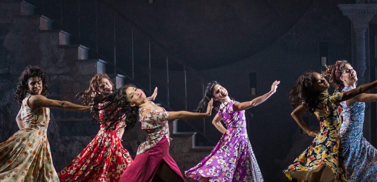 Six women dancing in unison on stage.