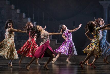 Six women dancing in unison on stage.