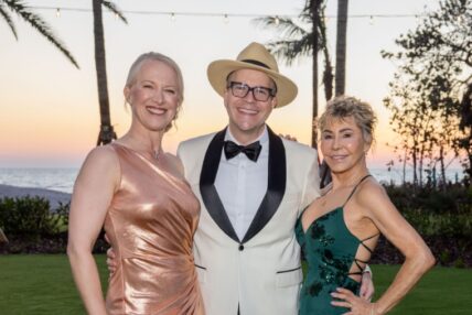 A man in a hat posing with two women in dresses at an Asolo Rep's Annual Gala.