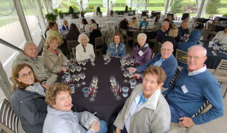 A group of older people sitting around a table smiling.