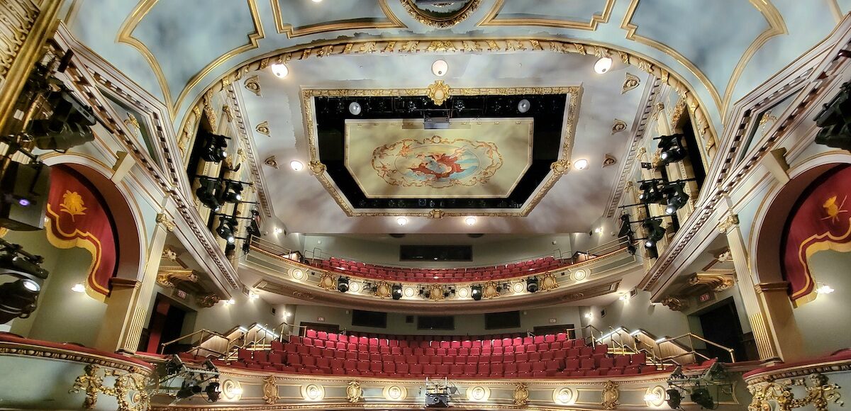 The interior of the Asolo Theatre with red seats, two balconies and an ornately painted ceiling.