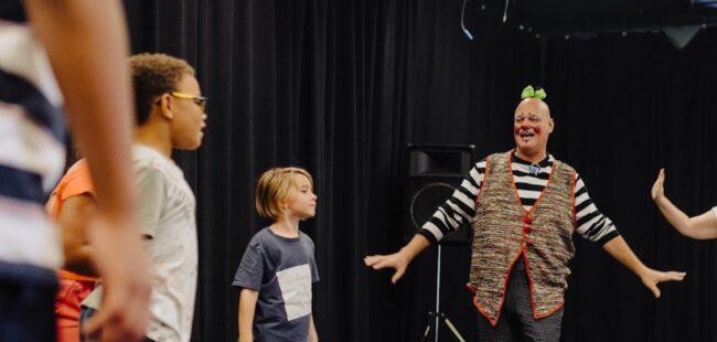 A clown leading children in a group activity.