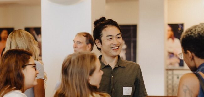 A group of young adults talk and smile.