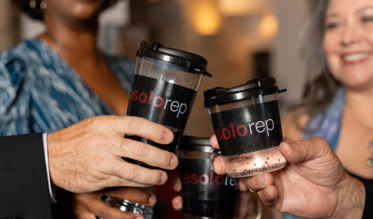 Four people clinking Asolo branded glasses in a toast.