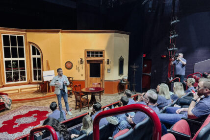 A seated audience looks at a speaker on stage.