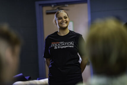 A teen participant of Asolo Rep's high school programming stands in front of a group smiling.