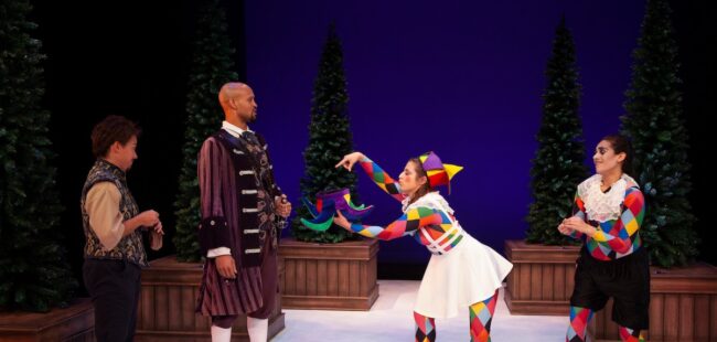 Two women dressed in jester outfits talking to two men.