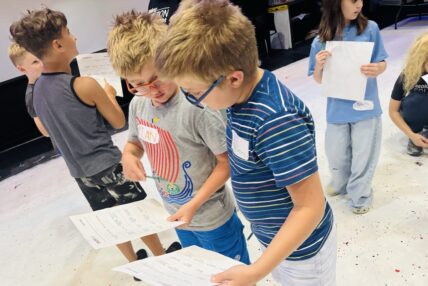 Two young boys comparing worksheets at an Asolo Rep youth program.