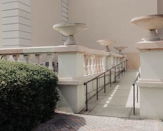 A wheelchair ramp with metal rails and ornate stone banisters.