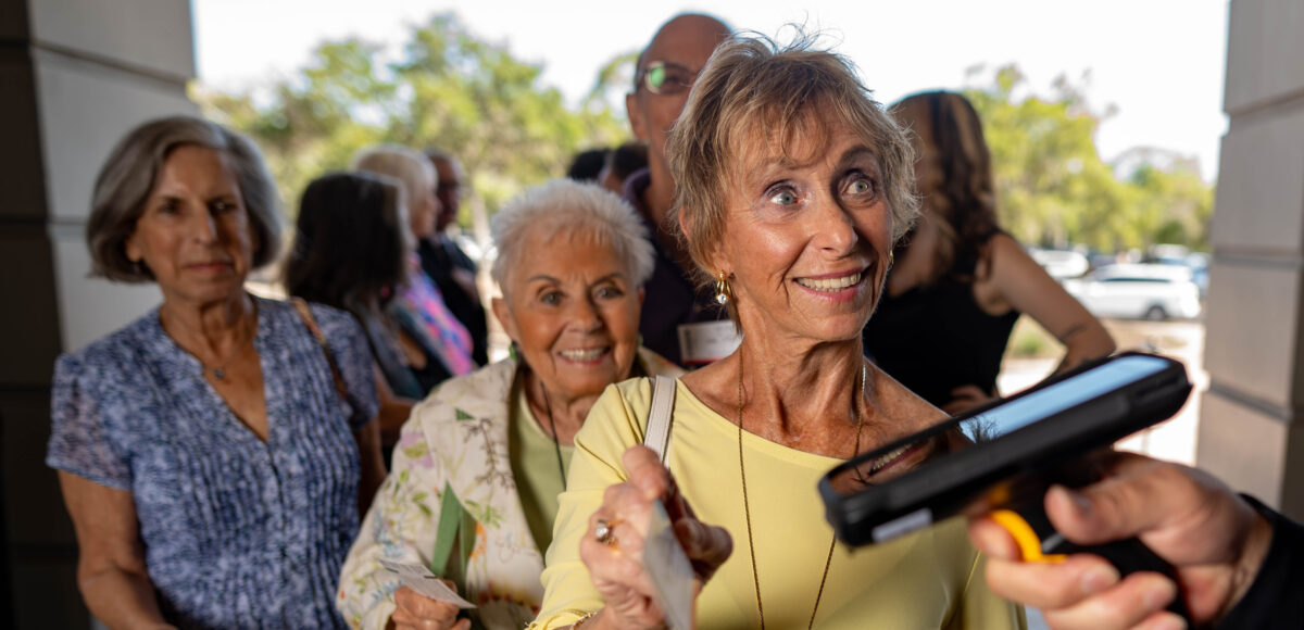 A theatre patron holding a ticket up to a hand-held scanner.