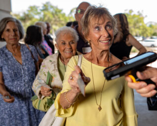 A theatre patron holding a ticket up to a hand-held scanner.