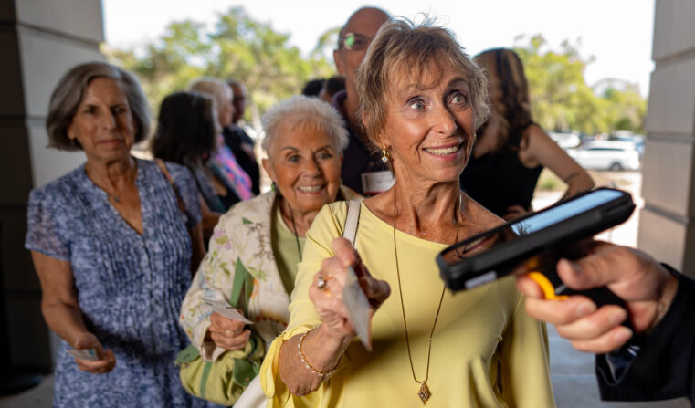 A theatre patron holding a ticket up to a hand-held scanner.