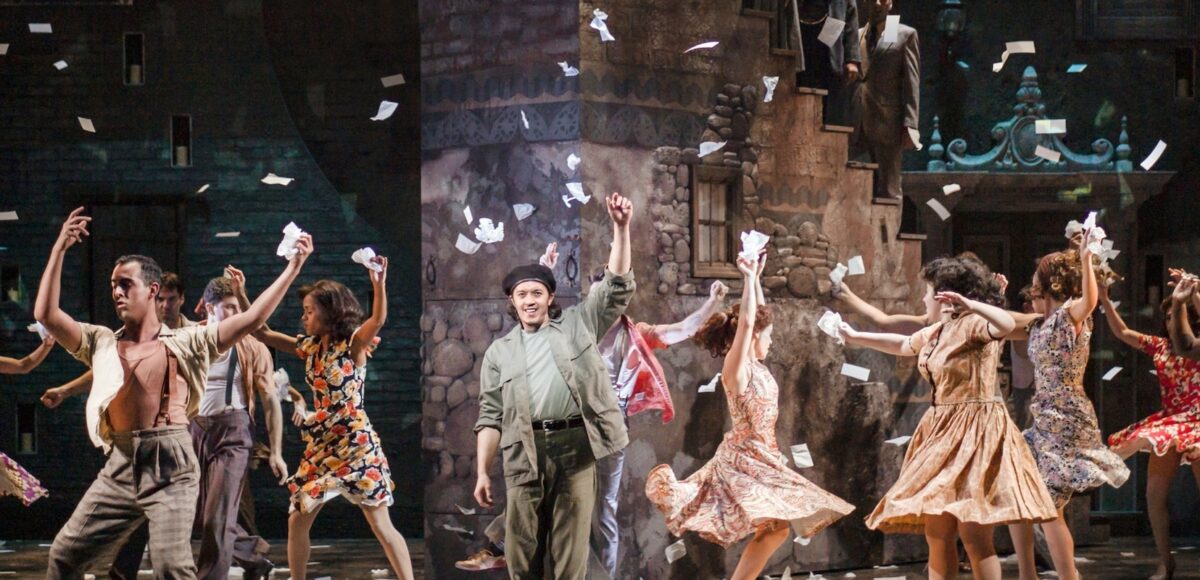 A group of men and women dancing and throwing paper in the air like confetti.