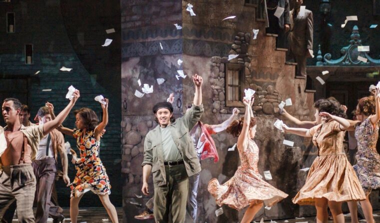 A group of men and women dancing and throwing paper in the air like confetti.