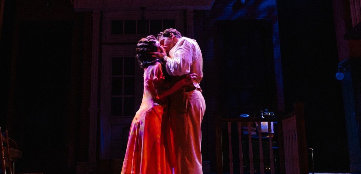 A man and a woman kissing on stage.