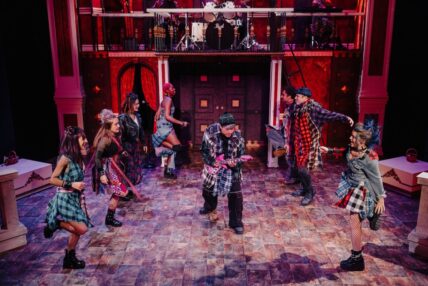 Eight performers in full grunge-punk costumes dancing on stage.