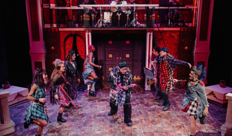 Eight performers in full grunge-punk costumes dancing on stage.