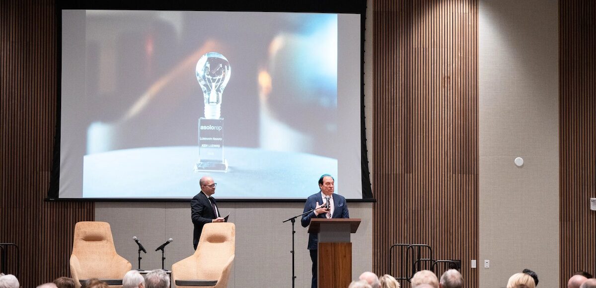 Two men speaking on stage to a group of people at Asolo Rep's Luminary Award ceremony.