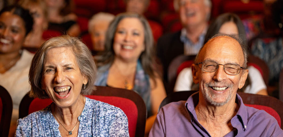 An older couple seated in the audience smiling.