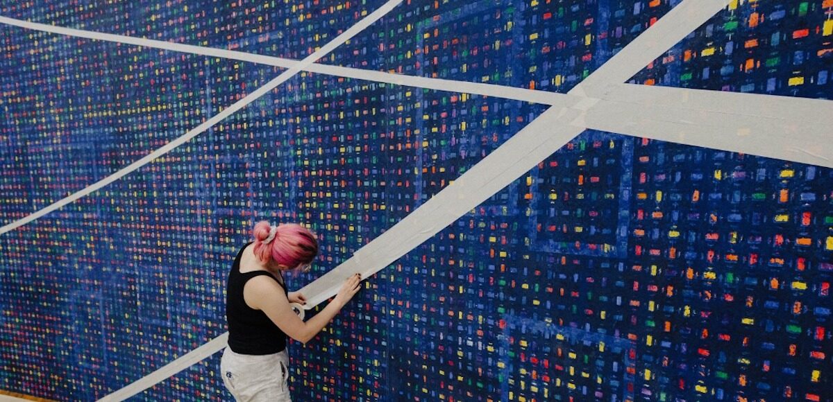 A woman taping off a colorful backdrop.