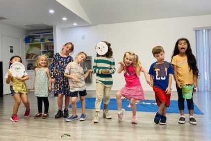 A group of young children making silly faces for a group photo.