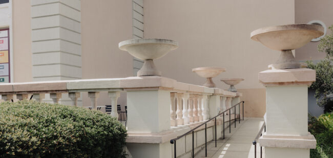 A wheelchair ramp with metal rails and ornate stone banisters.