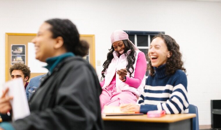 Four people sitting at desks and laughing.