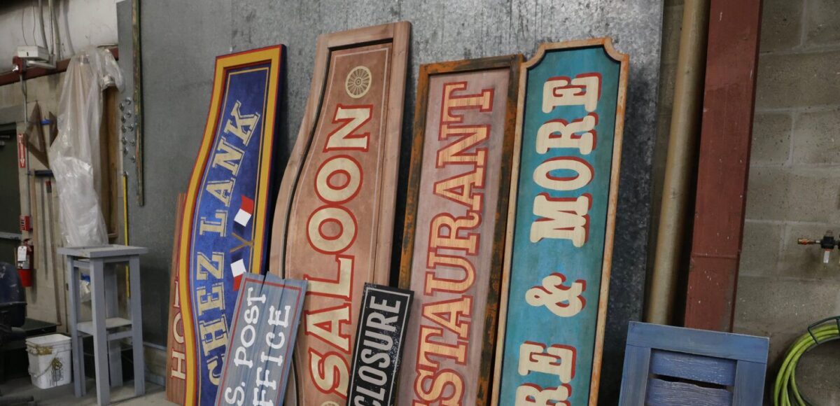 Decorative signage for a play leans against a wall.