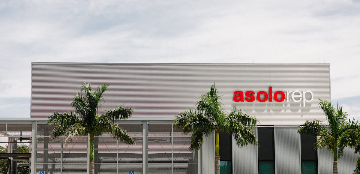 Exterior of an Asolo Rep's Koski Center building with three palm trees and ornamental grasses across the front.